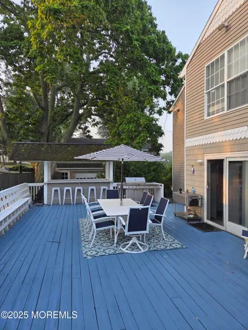 a view of a roof deck with table and chairs under an umbrella with wooden floor