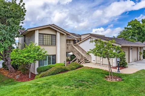 a view of a house with a big yard plants and large trees