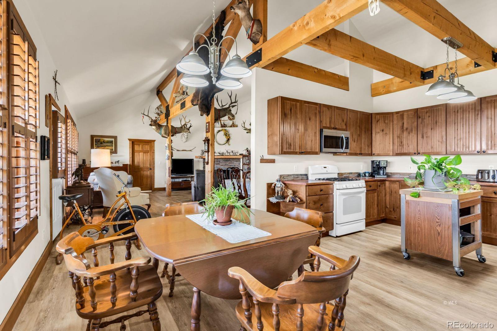 220 Rhonda Road Westcliffe, CO 81252 - Photo 8 of 35 a kitchen with a table chairs a sink dishwasher and a stove with wooden floor