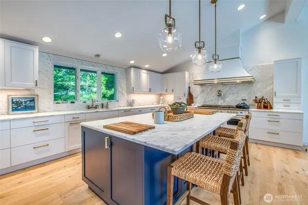 a kitchen with kitchen island granite countertop a sink a stove a dining table and chairs