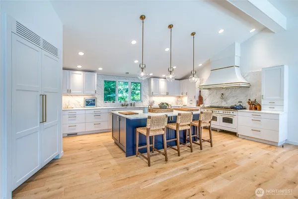 a kitchen with stainless steel appliances kitchen island granite countertop a table chairs and a view of living room