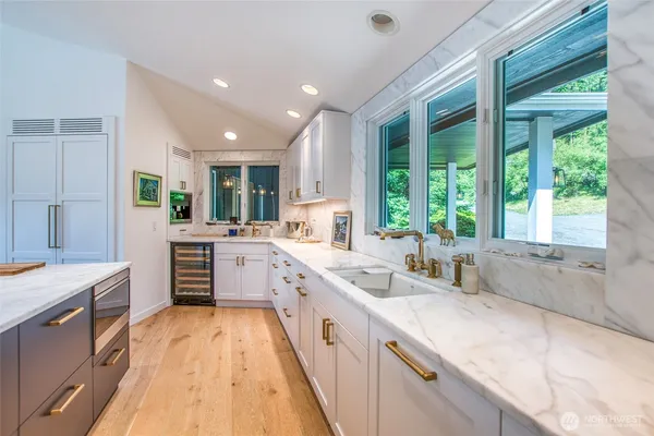 a large kitchen with stainless steel appliances granite countertop a large window and a sink