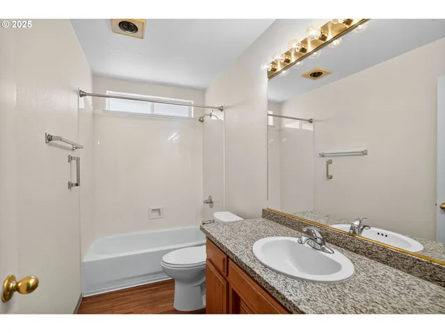 a bathroom with a granite countertop sink toilet a mirror and shower