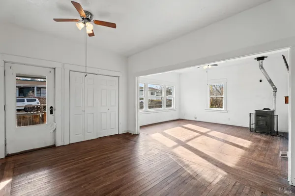 a view of empty room with wooden floor and fan
