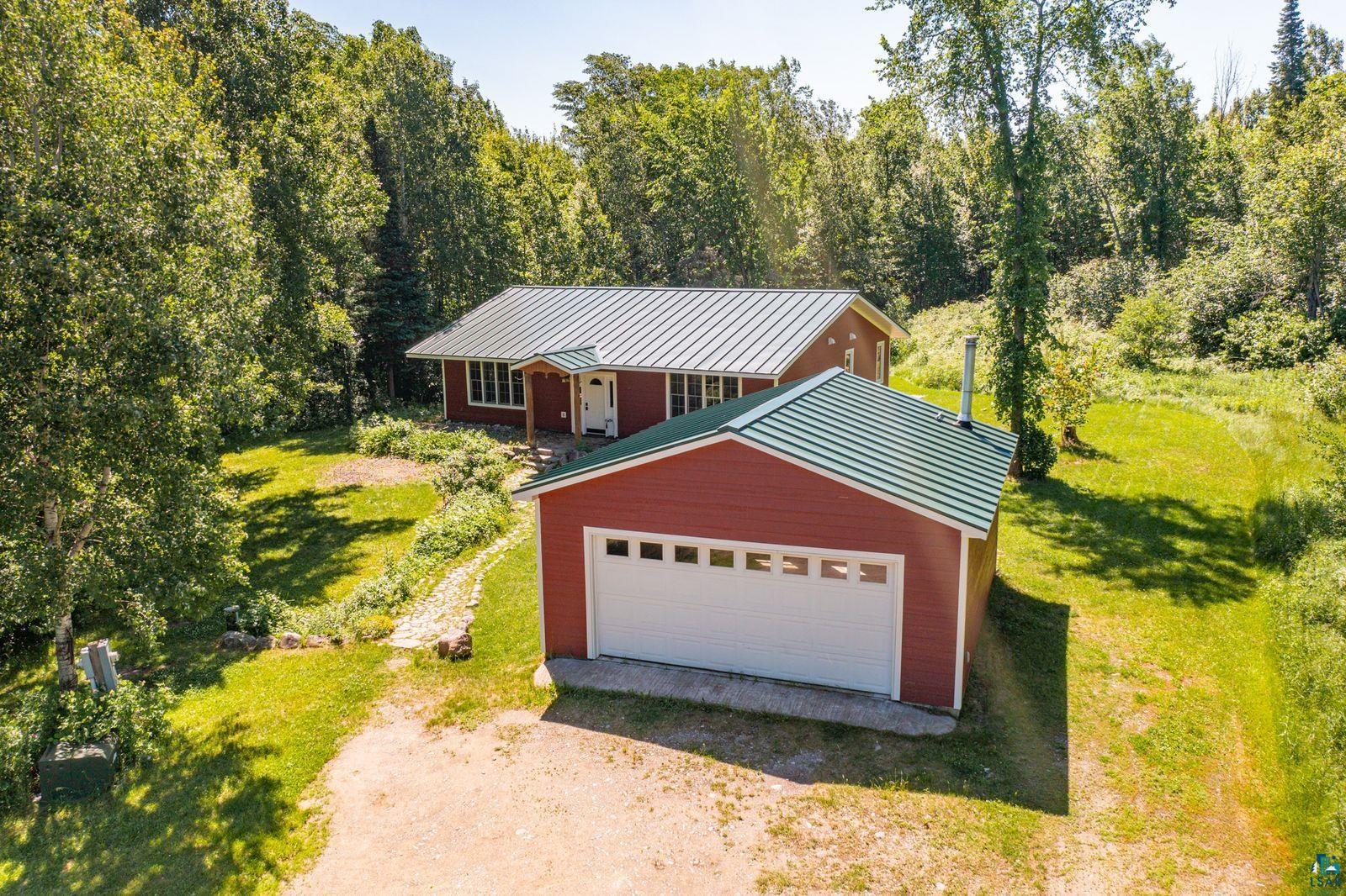 9734 Alango Road Angora, MN 55703 - Photo 28 of 41 Red-sided residence with an attached garage, featuring a bright white garage door