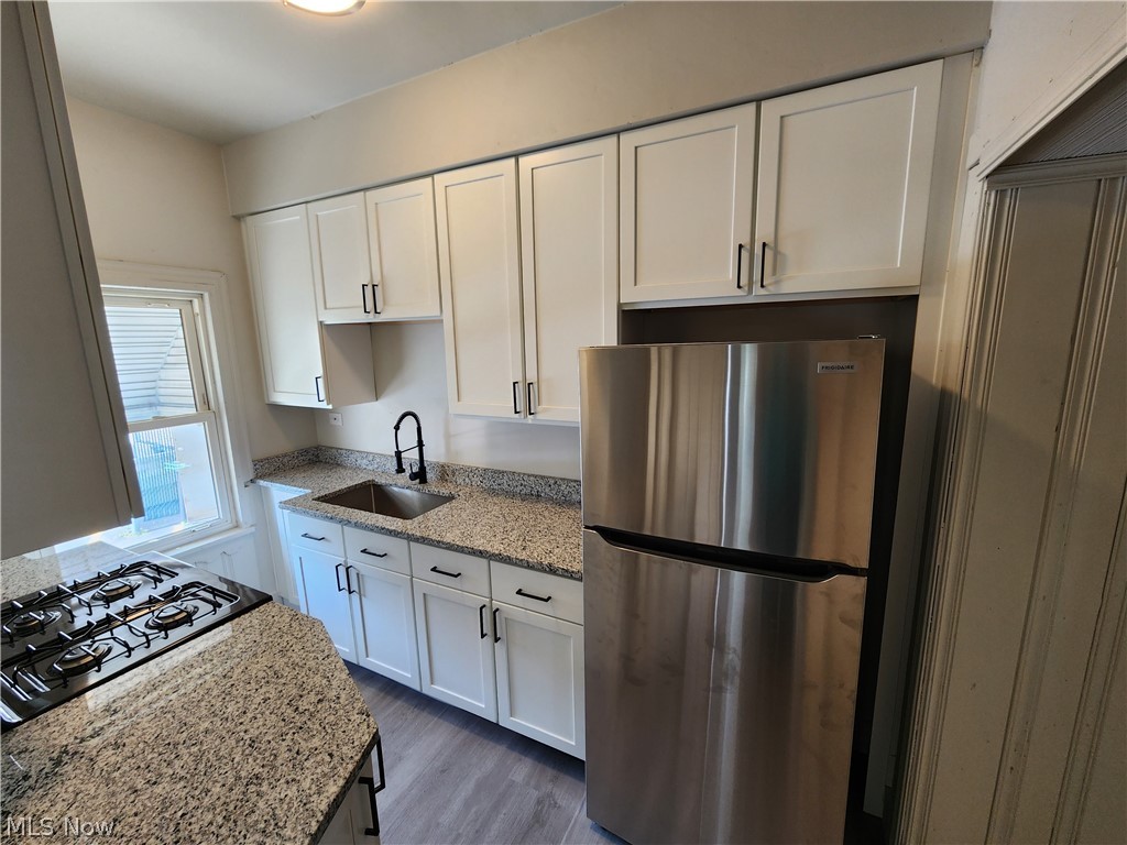 7202 Snow Road Parma, OH 44129 - Photo 6 of 14 Kitchen with sink, white cabinetry, dark wood-type flooring, stainless steel fridge, and black gas stovetop