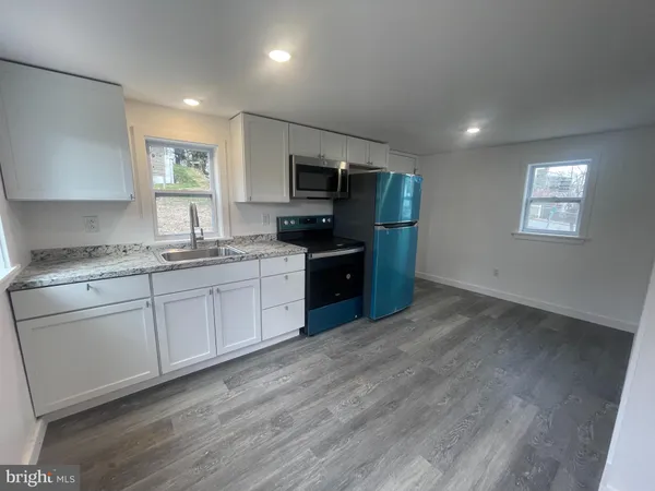 a kitchen with granite countertop a sink cabinets and stainless steel appliances
