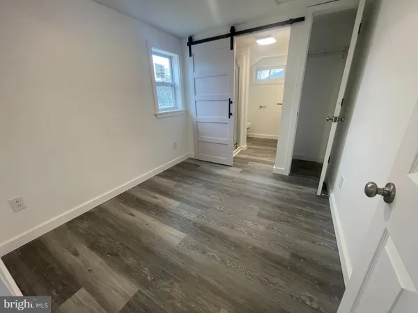 a view of an empty room with wooden floor and a mirror