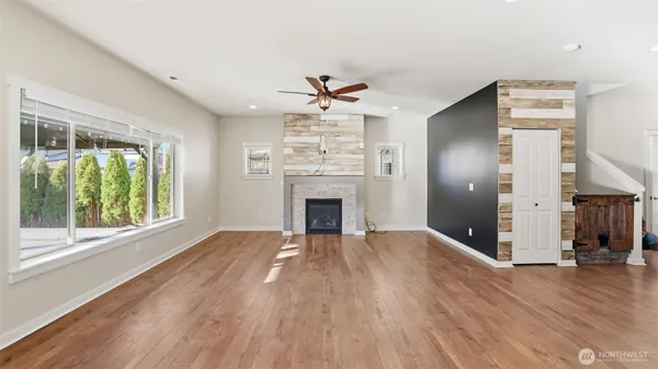 an empty room with wooden floor a fireplace and windows