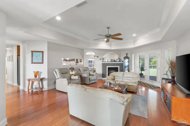 a view of a dining room and livingroom with furniture wooden floor a rug a fireplace and a chandelier