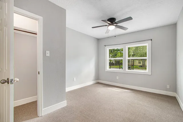 en empty room with ceiling fan and window
