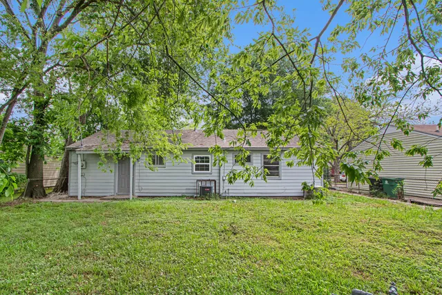 a view of a house with backyard and a tree