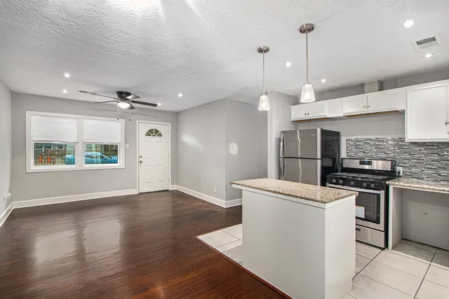 a kitchen with stainless steel appliances granite countertop a sink a stove a refrigerator and a dining table with wooden floor