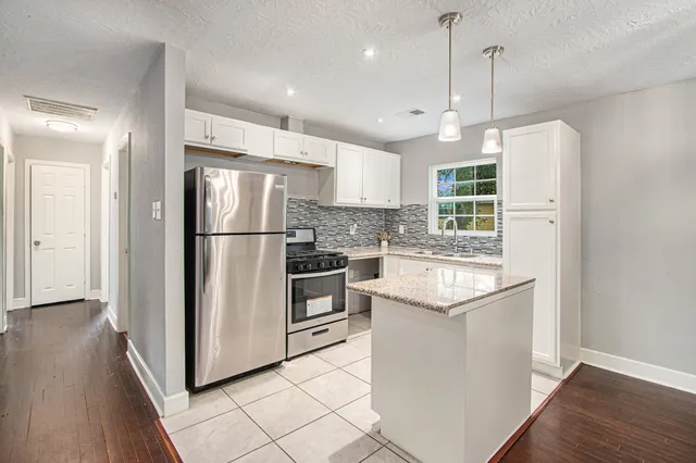 a kitchen with kitchen island white cabinets and stainless steel appliances