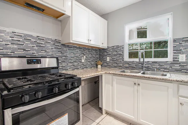 a kitchen with granite countertop a stove sink and cabinets