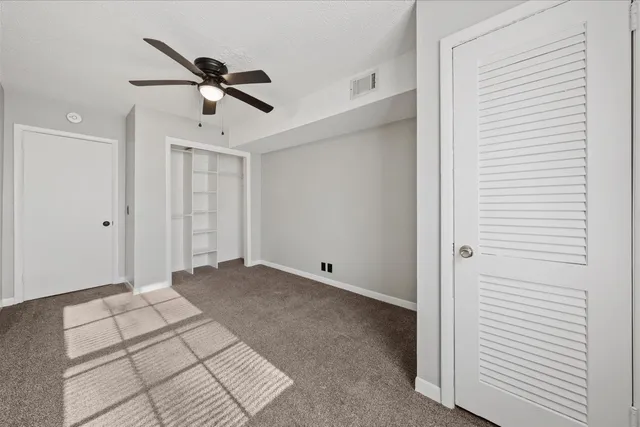 a view of empty room with stairs and a ceiling fan