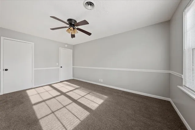 a view of a room with a ceiling fan and window