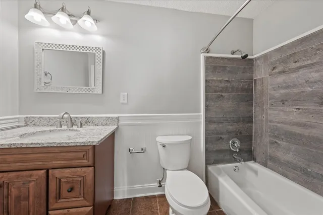 a bathroom with a granite countertop sink mirror vanity and toilet