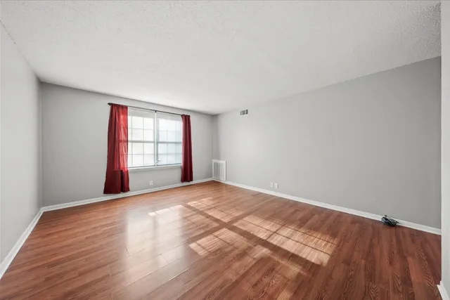 a view of an empty room with a window and wooden floor
