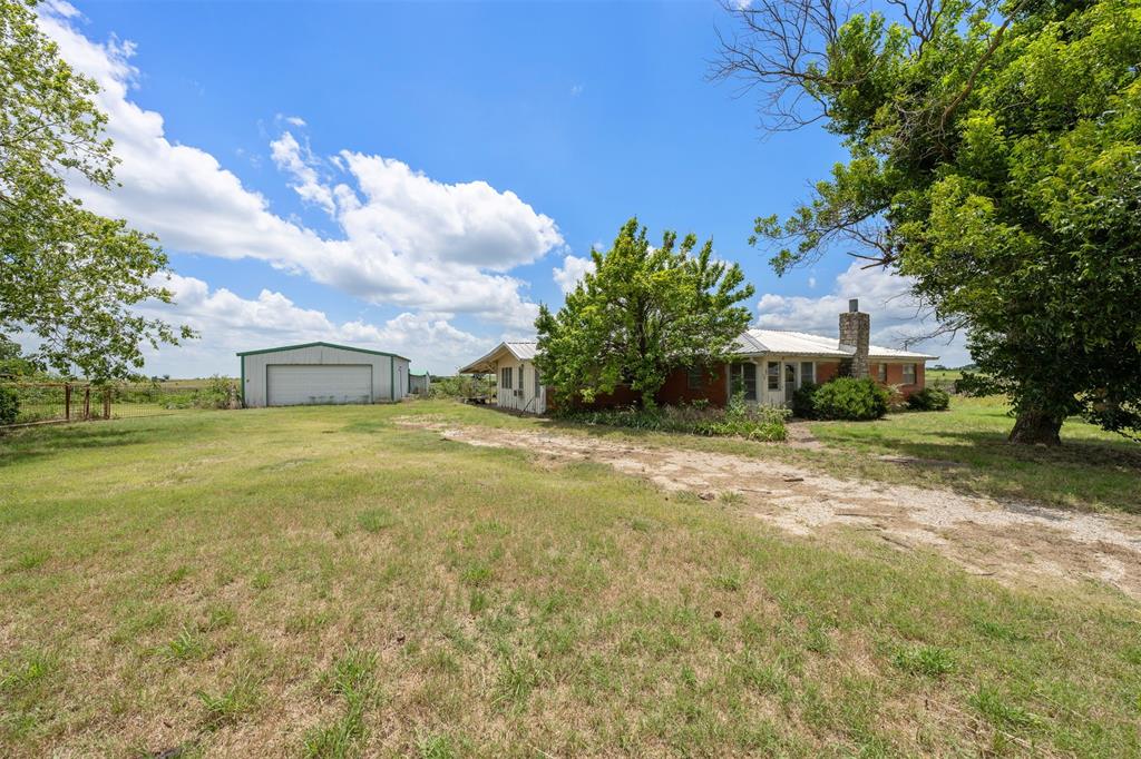 6450 Farm To Market Road 217 Valley Mills, TX 76689 - Photo 16 of 16 View of green lawn featuring a garage, an outbuilding, and dirt driveway