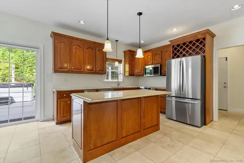 a kitchen with stainless steel appliances granite countertop a refrigerator a sink and wooden cabinets