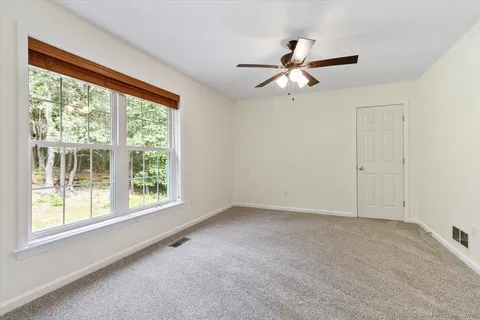 an empty room with windows and fan