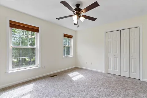 an empty room with windows and fan