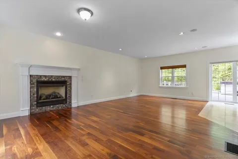 an empty room with wooden floor fireplace and windows