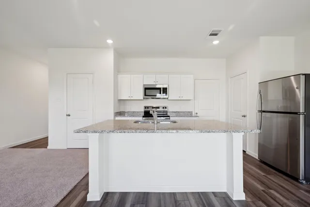 a kitchen with stainless steel appliances granite countertop a refrigerator a stove a sink a microwave and cabinets