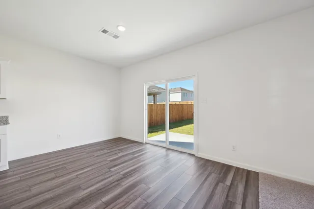 an empty room with wooden floor and glass door