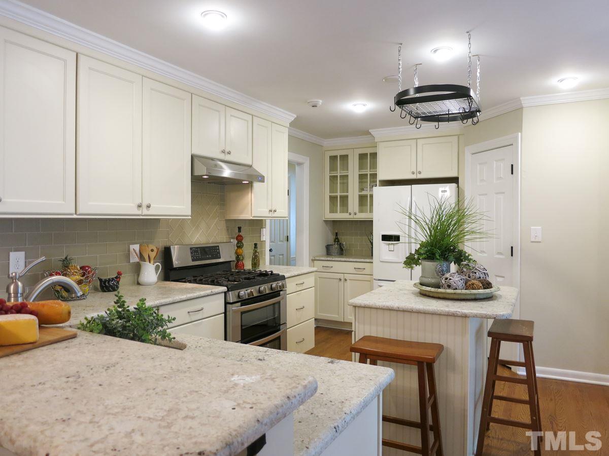 704 Currituck Drive Raleigh, NC 27609 - Photo 11 of 25 a kitchen with stainless steel appliances granite countertop a stove refrigerator a sink a dining table and chairs with wooden floor