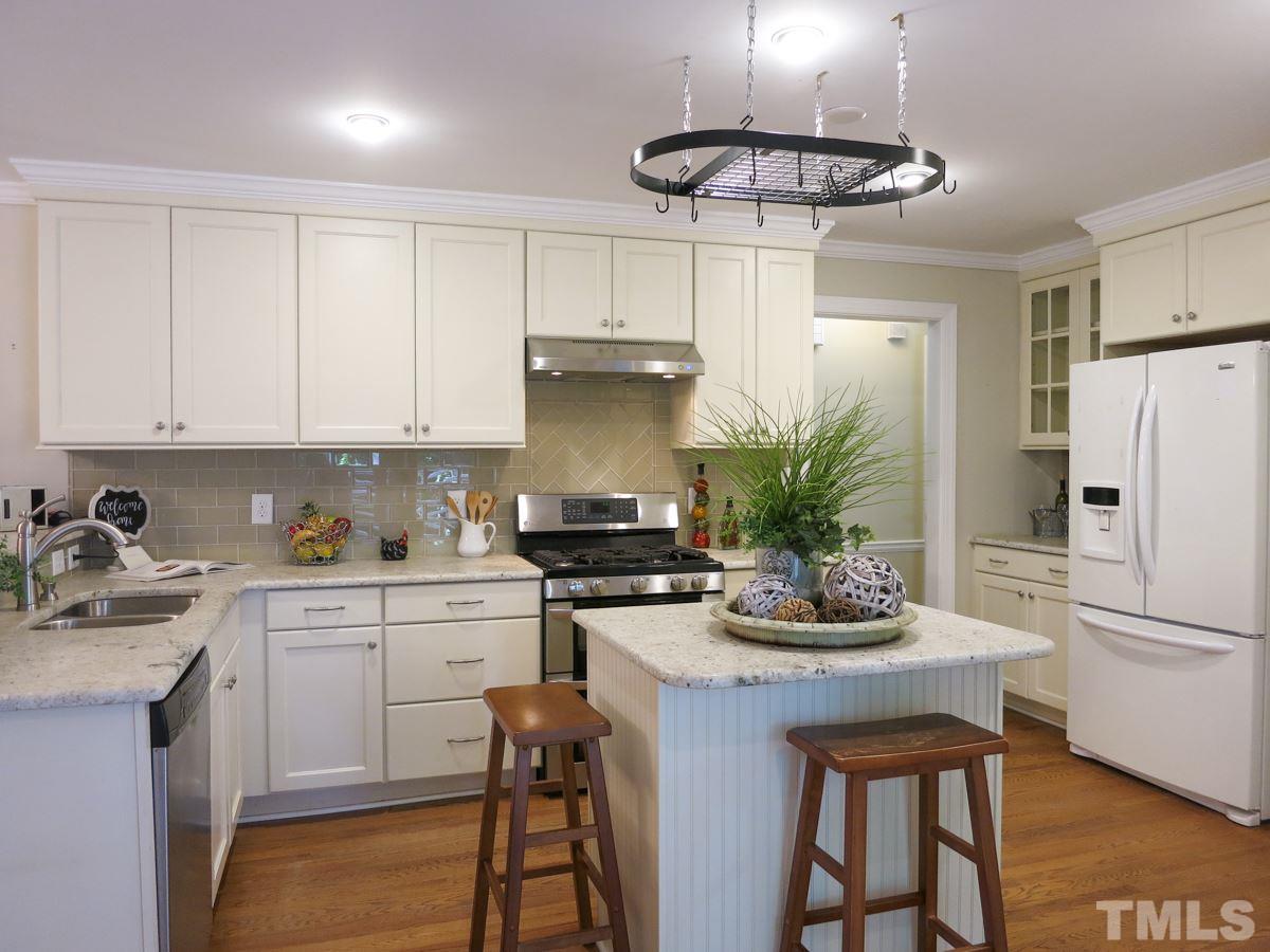 704 Currituck Drive Raleigh, NC 27609 - Photo 10 of 25 a kitchen with a refrigerator a stove a sink and cabinets