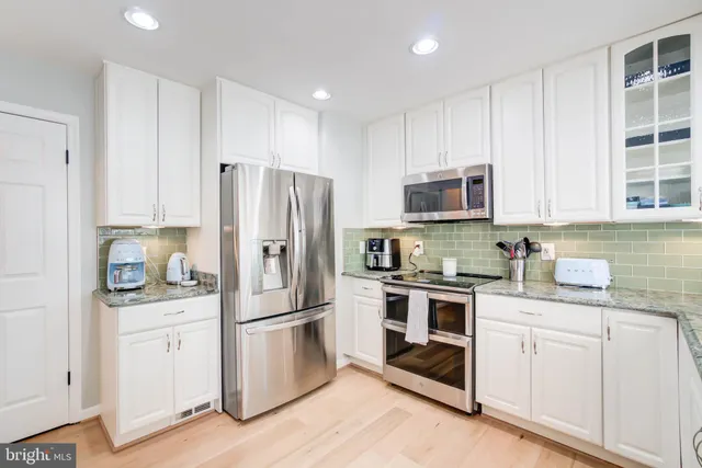 a kitchen with white cabinets and stainless steel appliances