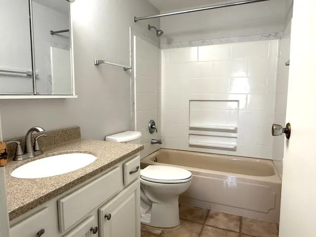 a bathroom with a granite countertop sink toilet and shower