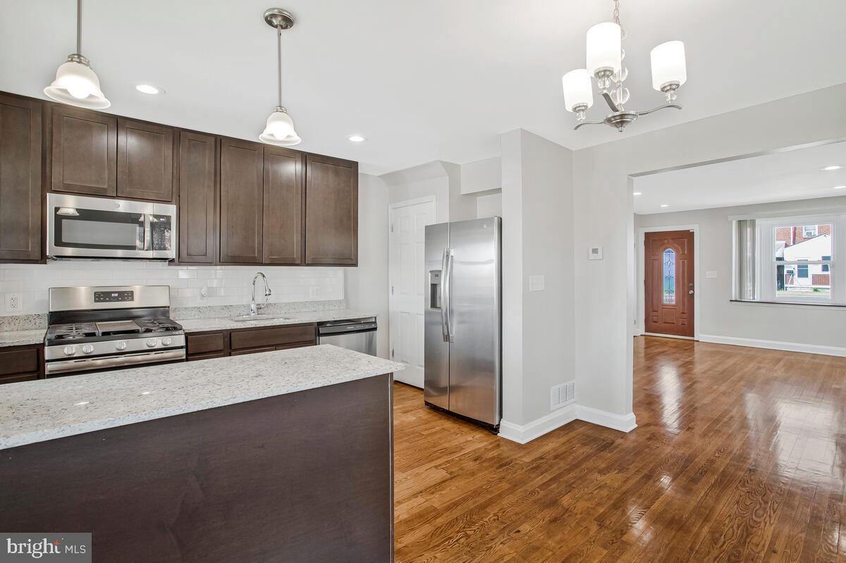 8352 Kavanagh Road Dundalk, MD 21222 - Photo 12 of 32 a large kitchen with stainless steel appliances granite countertop a refrigerator a stove a microwave oven a sink with island and chairs