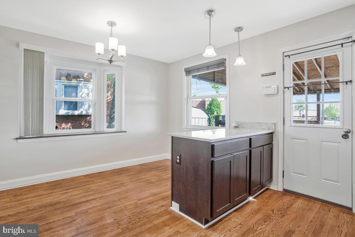 8352 Kavanagh Road Dundalk, MD 21222 - Photo 13 of 32 a kitchen with kitchen island granite countertop wooden floor and white appliances