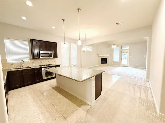 a large kitchen with kitchen island granite countertop a sink and a stove top oven with wooden floor