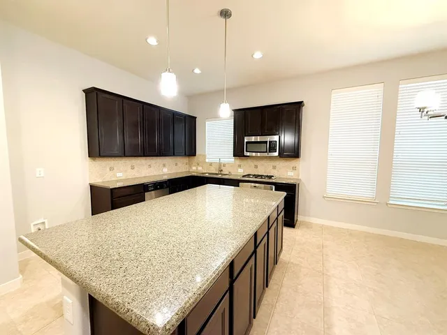 a kitchen with granite countertop a stove a sink and a microwave