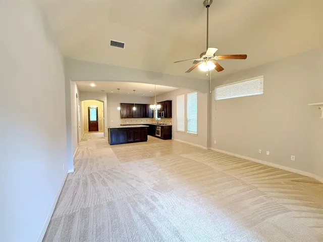 a view of a livingroom with a chandelier fan and kitchen view