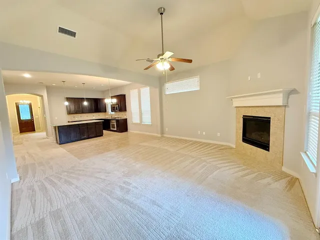 a view of an empty room with a kitchen and a fireplace