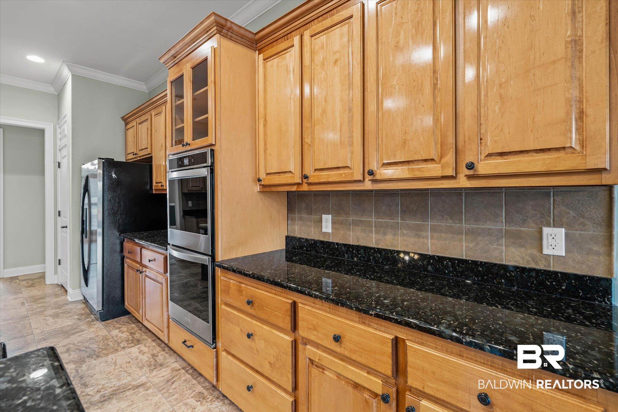 704 Edinburgh Avenue Foley, AL 36535 - Photo 14 of 32 Kitchen with crown molding, stainless steel appliances, glass insert cabinets, dark stone counters, and tasteful backsplash