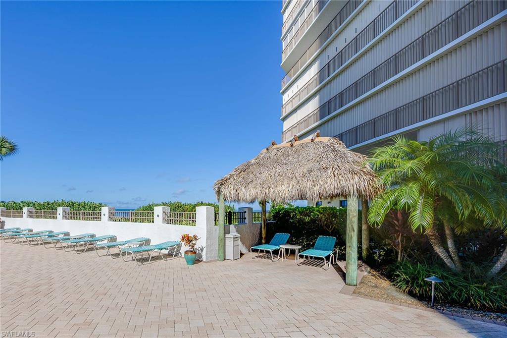 840 South Collier Boulevard, Unit 1104 Marco Island, FL 34145 - Photo 37 of 50 a view of a patio with a table and chairs under an umbrella with a small yard