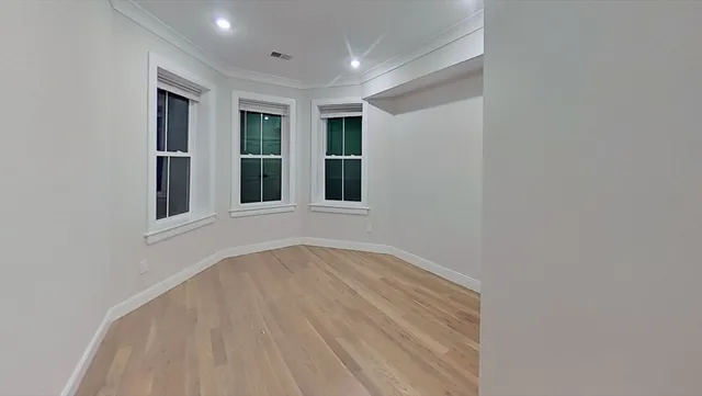 a view of an empty room with wooden floor and windows