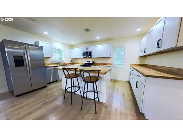 a open kitchen with stainless steel appliances granite countertop a refrigerator a sink dishwasher a stove with wooden floor