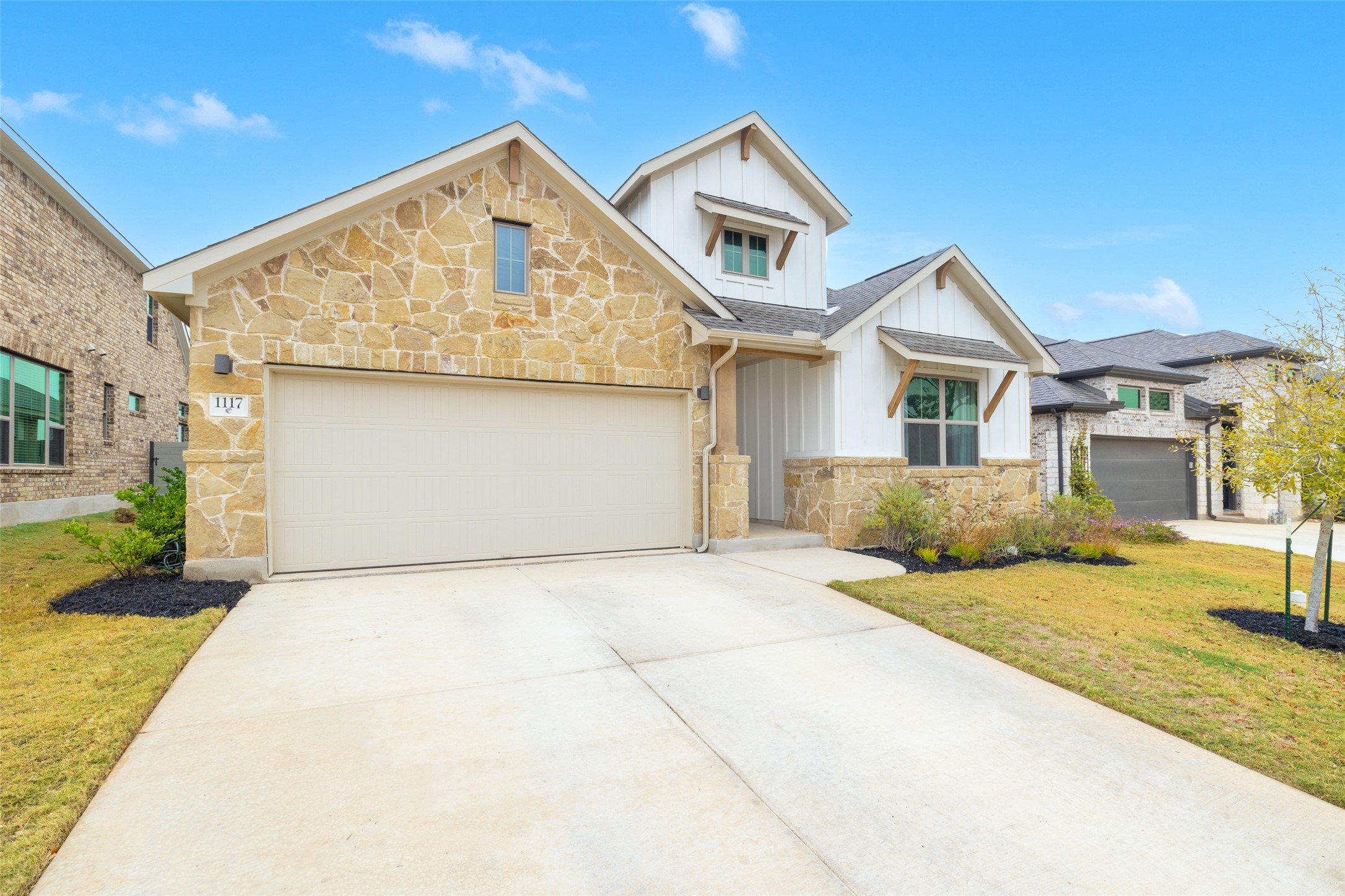 1117 Spring Gulch Lane Georgetown, TX 78628 - Photo 2 of 39 A charming exterior with a blend of natural stone and white siding, featuring a two-car garage and inviting entrance.