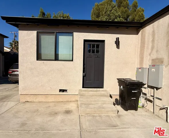 a front view of a house with barbeque grill and wooden fence