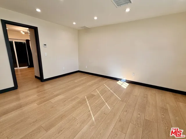 an empty room with wooden floor and entrance