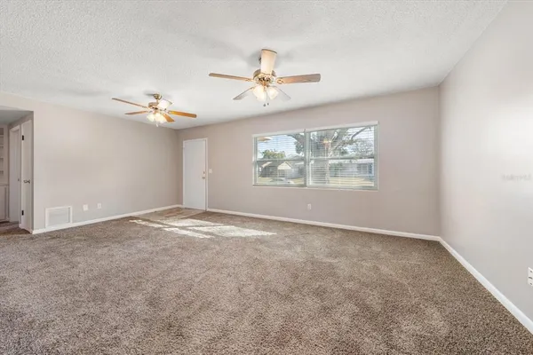 an empty room with windows and fan