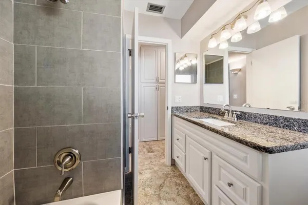 a bathroom with a granite countertop sink a mirror and a shower