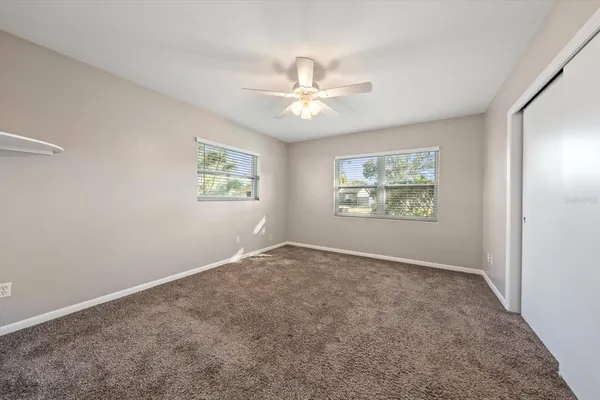 an empty room with windows and fan